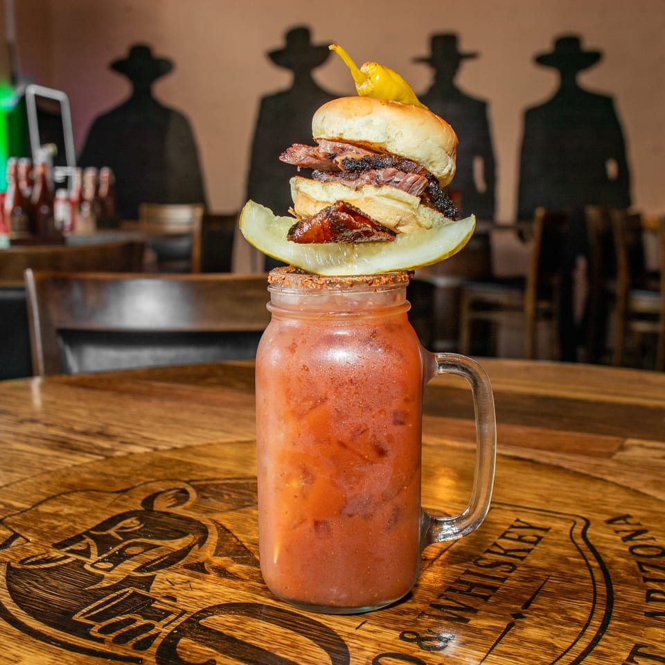 A Bloody Mary in a mason jar, topped with a brisket slider, pickle, and pepper.